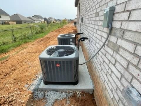 Two new outdoor AC condenser units installed next to a brick building by Diversified Services NA in Rogers, AR.