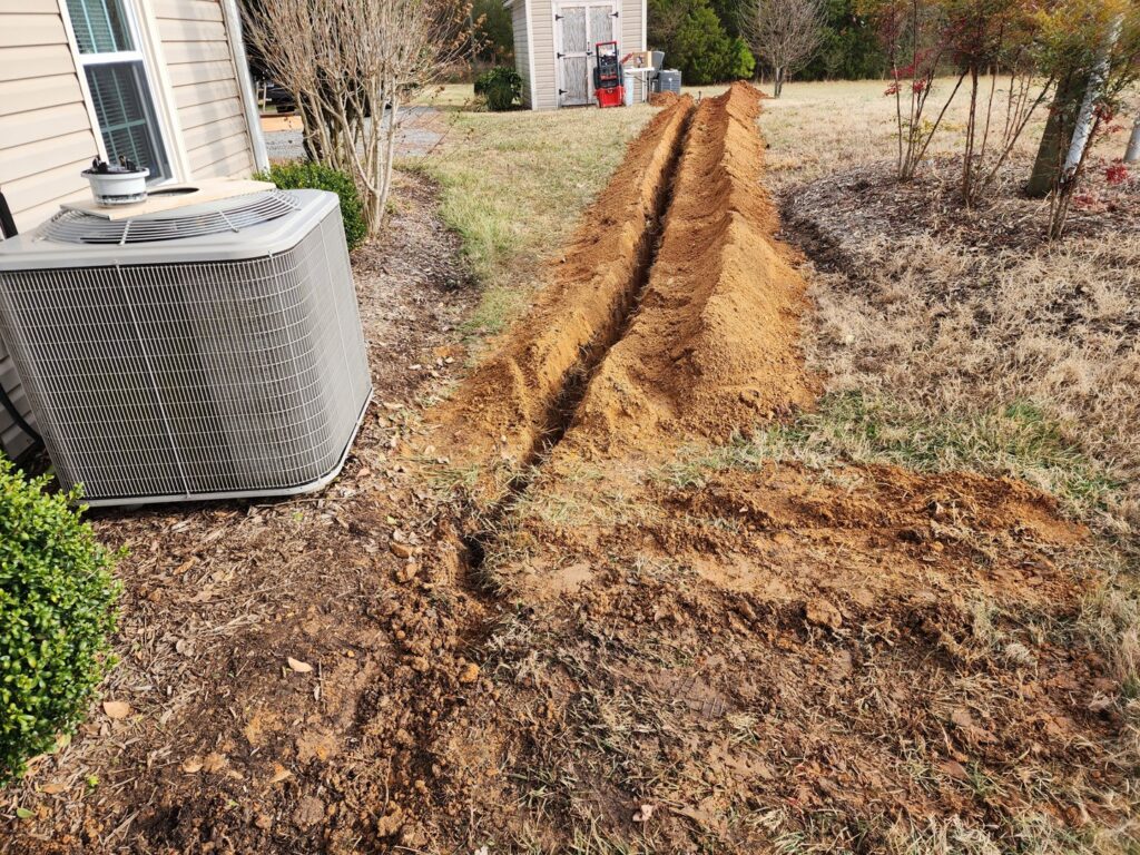 An outdoor AC unit next to a trench for new line installation by Woodfin-Your Home Team in Richmond, VA.