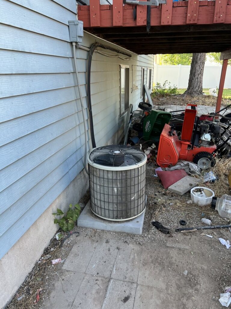 An outdoor air conditioning unit located in a backyard, ready for service by TriForce HVAC in Layton, UT