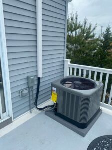 An outdoor AC unit installed on a residential balcony by Tom's Heating & Air Conditioning LLC in Lacey Township, NJ.