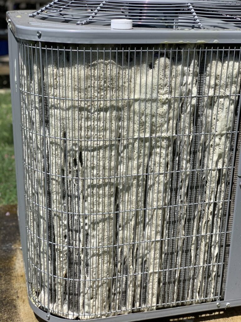 An outdoor AC unit being cleaned with foam, indicating maintenance work by Airtegrity Comfort Solutions in San Antonio, TX