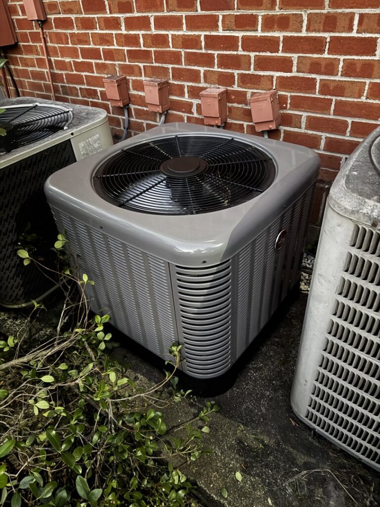 An outdoor AC unit positioned next to a brick wall, maintained by OnPoint Heating and Air in Commerce City, CO.