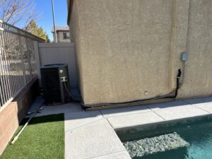 An outdoor air conditioning unit installed next to a swimming pool by The Heating & Cooling Company LLC in Las Vegas, NV.