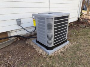 An outdoor air conditioning condenser unit installed next to a residential building by A-1 HVAC in Kansas City, KS.