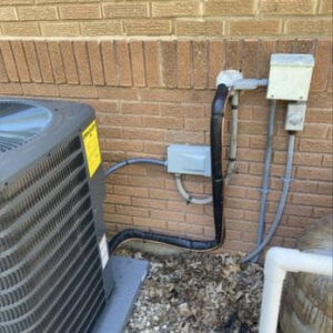 Close-up of the refrigerant lines and electrical connections for an outdoor AC unit, serviced by Lopez Mechanical HVAC in Kansas City, MO.