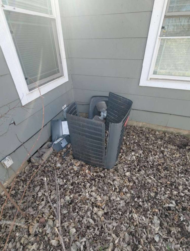 An outdoor air conditioning unit partially disassembled next to a house by Friess Heating & Air Conditioning in Topeka, KS