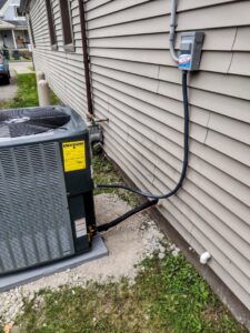 An outdoor AC unit with electrical connections installed by Total Comfort Heat and Air Conditioning, Inc. in Rochester, NY.