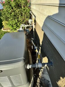 An outdoor AC unit with gas lines and utility connections installed by Woodfin-Your Home Team in Richmond, VA.