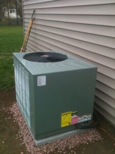 An outdoor air conditioning unit installed on a gravel bed next to a house by Accurate Conditioning in Sayreville, NJ.