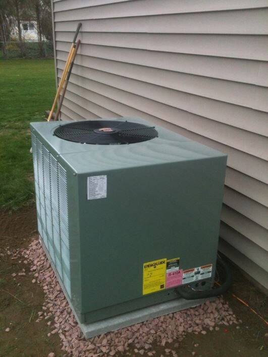 An outdoor air conditioning unit installed on a gravel bed next to a house by Accurate Conditioning in Sayreville, NJ.