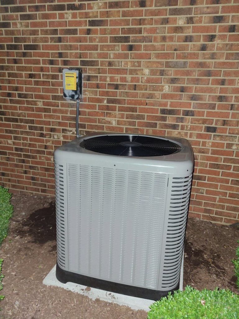 An outdoor air conditioning unit installed next to a brick wall by Adam's Air Conditioning & Heating in Rockvale, TN