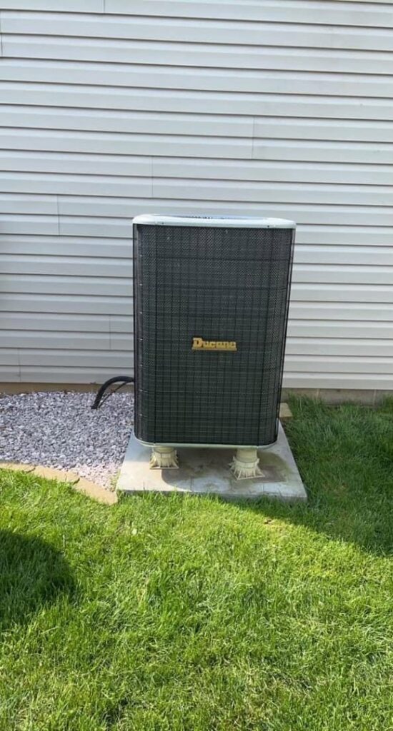 An outdoor air conditioning unit installed next to a residential building by Affordable Heating & Cooling in Lafayette, IN.