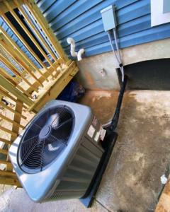 An outdoor air conditioning unit installed next to a home with blue siding by Vico&Son HVAC Services and Sheet Metal LLC in Beltsville, MD.