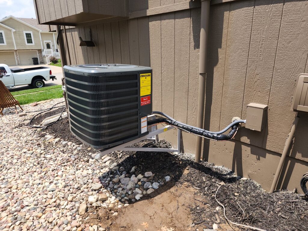 An outdoor air conditioning unit newly installed on a wall bracket by Dad's Heating and Cooling in Blue Springs, MO.