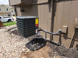 An outdoor air conditioning unit newly installed on a wall bracket by Dad's Heating and Cooling in Blue Springs, MO.