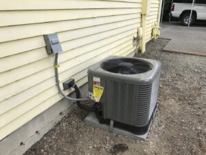 An outdoor air conditioning unit installed next to a yellow house by Columbia Heating & Air Conditioning in Kent, WA.