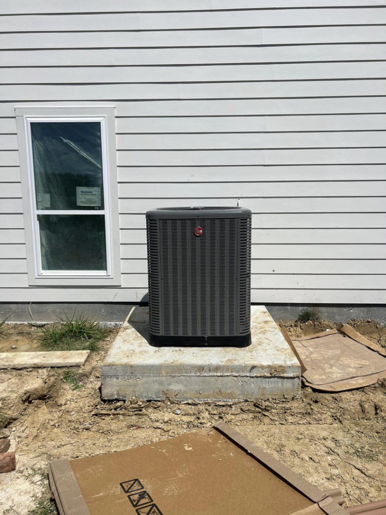 An outdoor Rheem AC unit installed next to a new house by Comfort Zone AC and Heating Services LLC in Sunrise Beach, MO