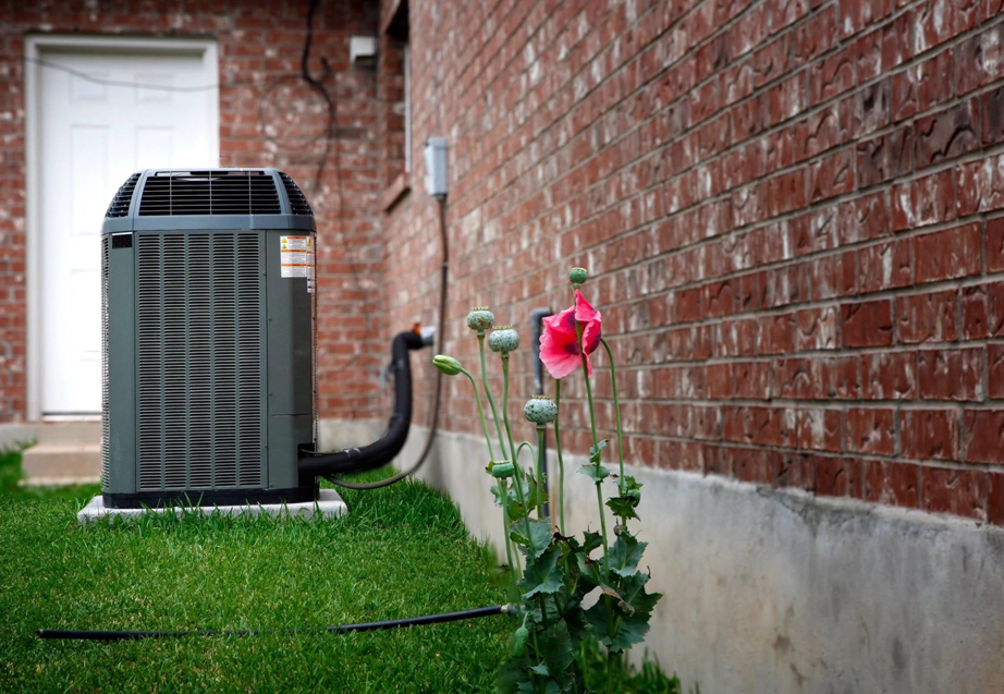 An outdoor air conditioning unit installed next to a brick home by Dwyers heating & cooling in Overland, MO.