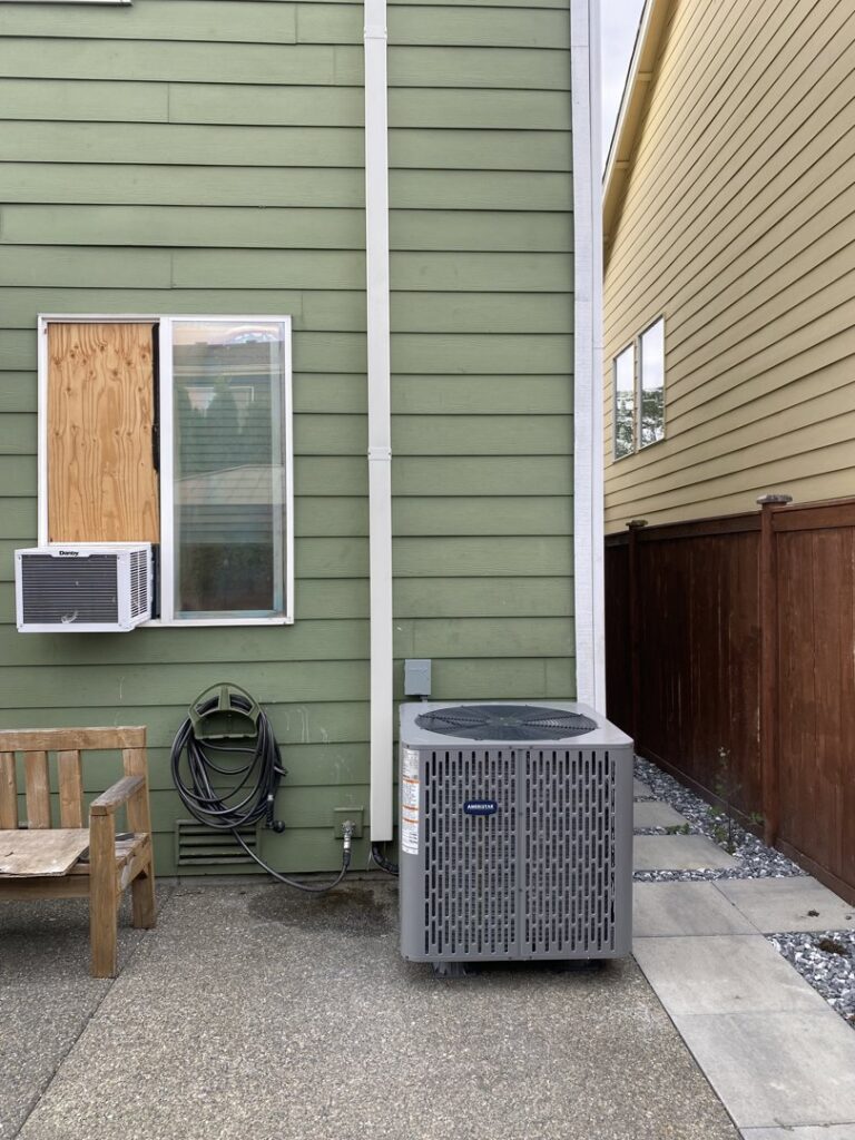 An outdoor Carrier air conditioning unit installed next to a home by Heatwave Heating & Air LLC in Federal Way, WA.