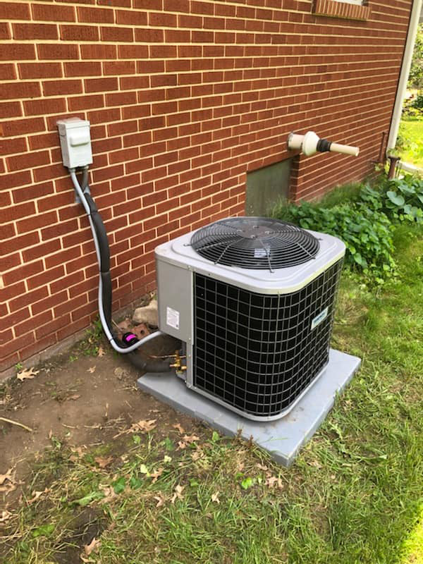 A newly installed outdoor air conditioning unit next to a brick home by Hobart Heating & Cooling Inc. in East Peoria, IL.