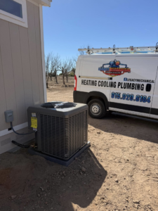An outdoor AC unit installation next to a building with the Legacy Mechanical LLC service van in Sunland Park, NM.