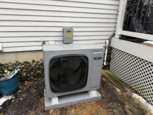 A newly installed outdoor AC unit next to a residential building by Lighthouse HVAC, LLC in Edgewater, MD.