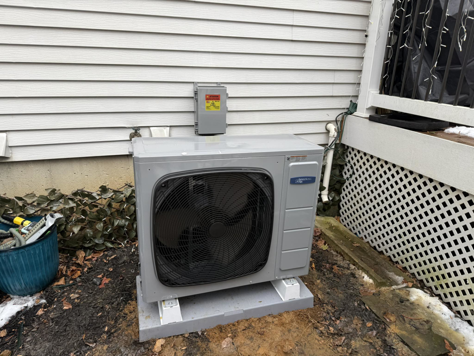 A newly installed outdoor AC unit next to a residential building by Lighthouse HVAC, LLC in Edgewater, MD.