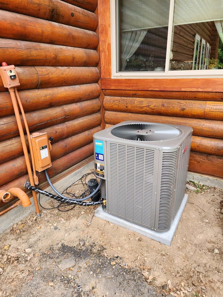 A newly installed outdoor air conditioning unit next to a log cabin home by Greens Heating & Air Conditioning in Douglasville, GA.