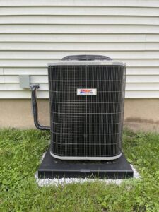 An outdoor air conditioning unit installed next to a residential building by MAC Heating and Cooling LLC in Waterbury, CT.
