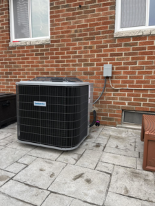 An outdoor Comfortmaker AC unit installed next to a brick house by Motown Mechanical Heating And Cooling in Westland, MI.
