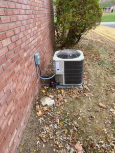 An outdoor air conditioning unit installed next to a brick wall by R. Jones Heating & Cooling in Indianapolis, IN.
