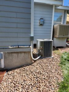 An outdoor air conditioning unit installed next to a residential home by D & D Heating & Air in Brighton, CO.