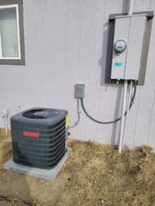 An outdoor Goodman AC unit installation next to a residential building by Rural Heating and Cooling Systems in Roundup, MT.