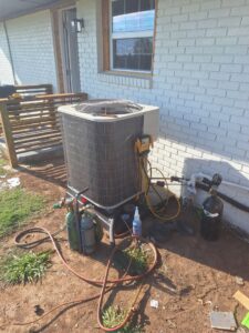 An outdoor AC unit with refrigerant tanks and tools during installation or service by The Right Flow Heating and Air LLC in Lawton, OK