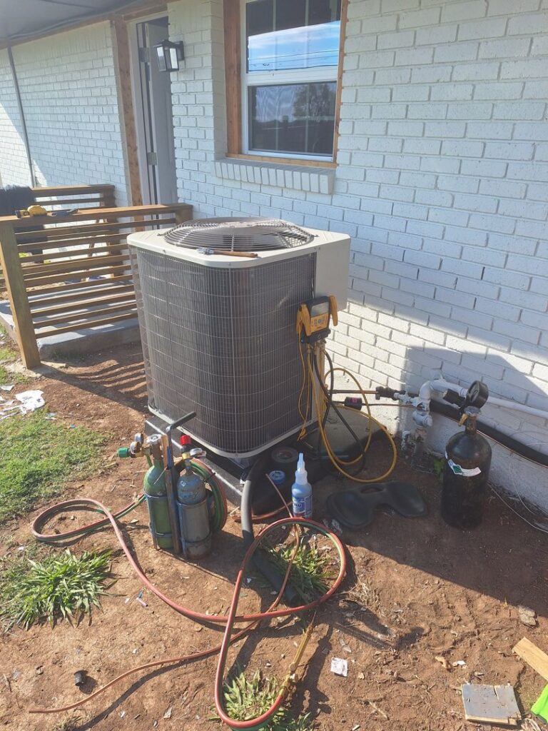 An outdoor AC unit with refrigerant tanks and tools during installation or service by The Right Flow Heating and Air LLC in Lawton, OK