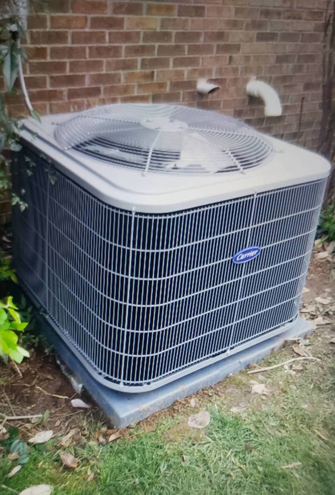 An outdoor Carrier air conditioning unit installed next to a brick wall by Temperature Comfort Heating and Cooling in Louisville, KY.
