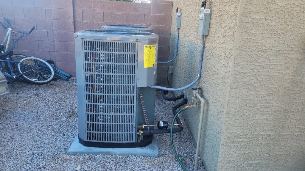 An outdoor AC unit newly installed next to a residential building by Vertex Heating & Cooling in Buckeye, AZ