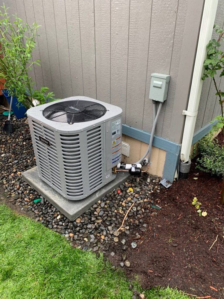 An outdoor air conditioning unit integrated with landscaping by Excellence Heating & Cooling, LLC. in Beaverton, OR.