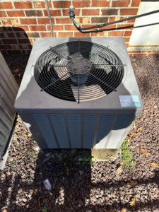 An outdoor air conditioning unit on a bed of rocks, maintained by EndorFin Service's Inc. Heating & Air Conditioning in Gloucester, VA.