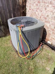 An outdoor AC condenser unit undergoing maintenance with manifold gauges connected by TAG Heat N Air in North Little Rock, AR.