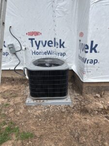 A newly installed outdoor air conditioning unit next to a house under construction by TriForce HVAC in Layton, UT