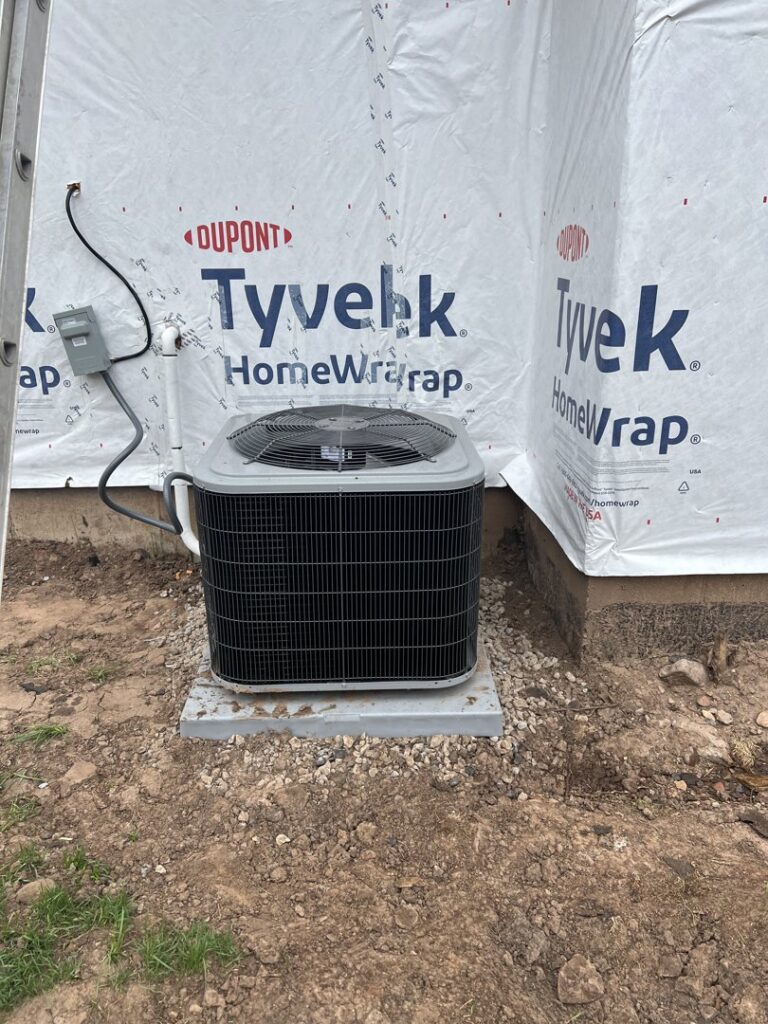 A newly installed outdoor air conditioning unit next to a house under construction by TriForce HVAC in Layton, UT