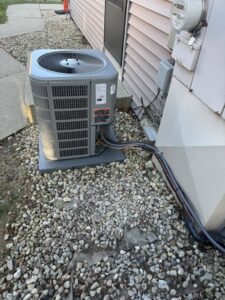 An outdoor air conditioning unit with connected refrigerant lines, installed by Nordic Air Heating & Cooling in West Allis, WI.
