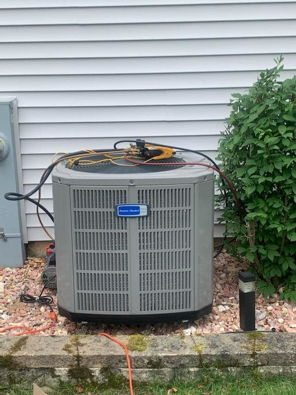 An outdoor American Standard AC unit undergoing repair or maintenance by 365 Heating & Cooling in North Aurora, IL.