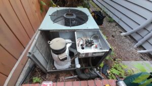 An outdoor AC condenser unit with its top panel removed, showing internal components during a repair or service by PNW Spokane Heating and Air in Spokane, WA.