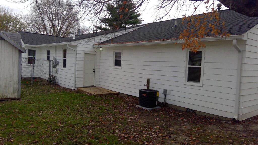 An outdoor air conditioning unit installed next to a residential home by Basic HVAC in Indianapolis, IN.