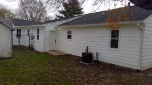 An outdoor air conditioning unit installed next to a residential home by Basic HVAC in Indianapolis, IN.