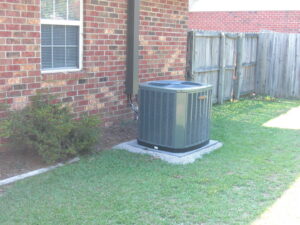 An outdoor air conditioning unit installed next to a brick residential home by Boykin Air Conditioning Services in Sumter, SC.