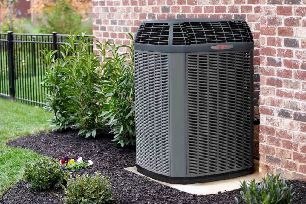 A modern outdoor air conditioning unit installed next to a residential brick home by Elite Home Comfort in Clarksville, TN