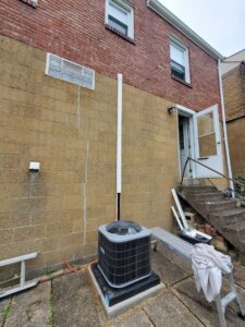 An outdoor air conditioning unit installed next to a residential building by Bouvy Heating & Air Conditioning Services in Pittsburgh, PA.